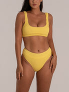 Angled view of high-rise mustard yellow bikini bottom with body-hugging fabric