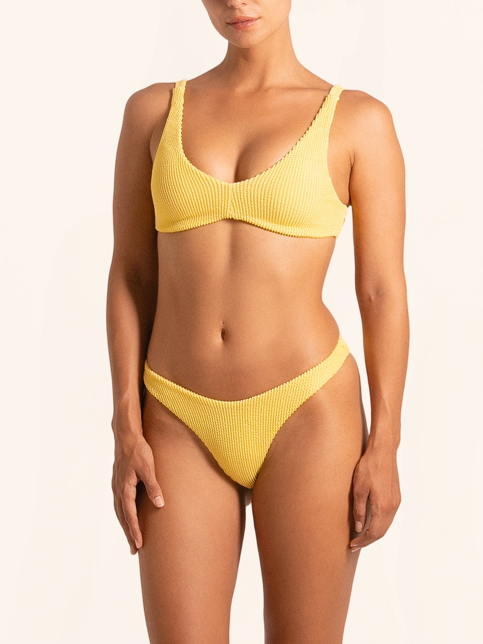 Front view of mustard yellow bikini bottom with textured fabric and high leg cut.