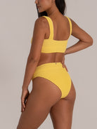 Side-back angle showing mustard yellow bikini bottom in textured stretch fabric