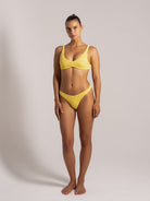 Woman wearing mustard yellow textured bikini set, front view showing scoop neck top and mid-rise bottoms