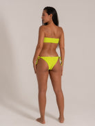Model wearing neon yellow textured bandeau bikini set, back view with side-tie bottoms