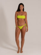 Front view of model wearing neon yellow textured bandeau bikini with tie-side bottoms