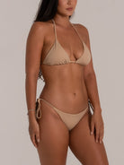 Angled view of model in minimalist nude triangle bikini set with halter top and side ties