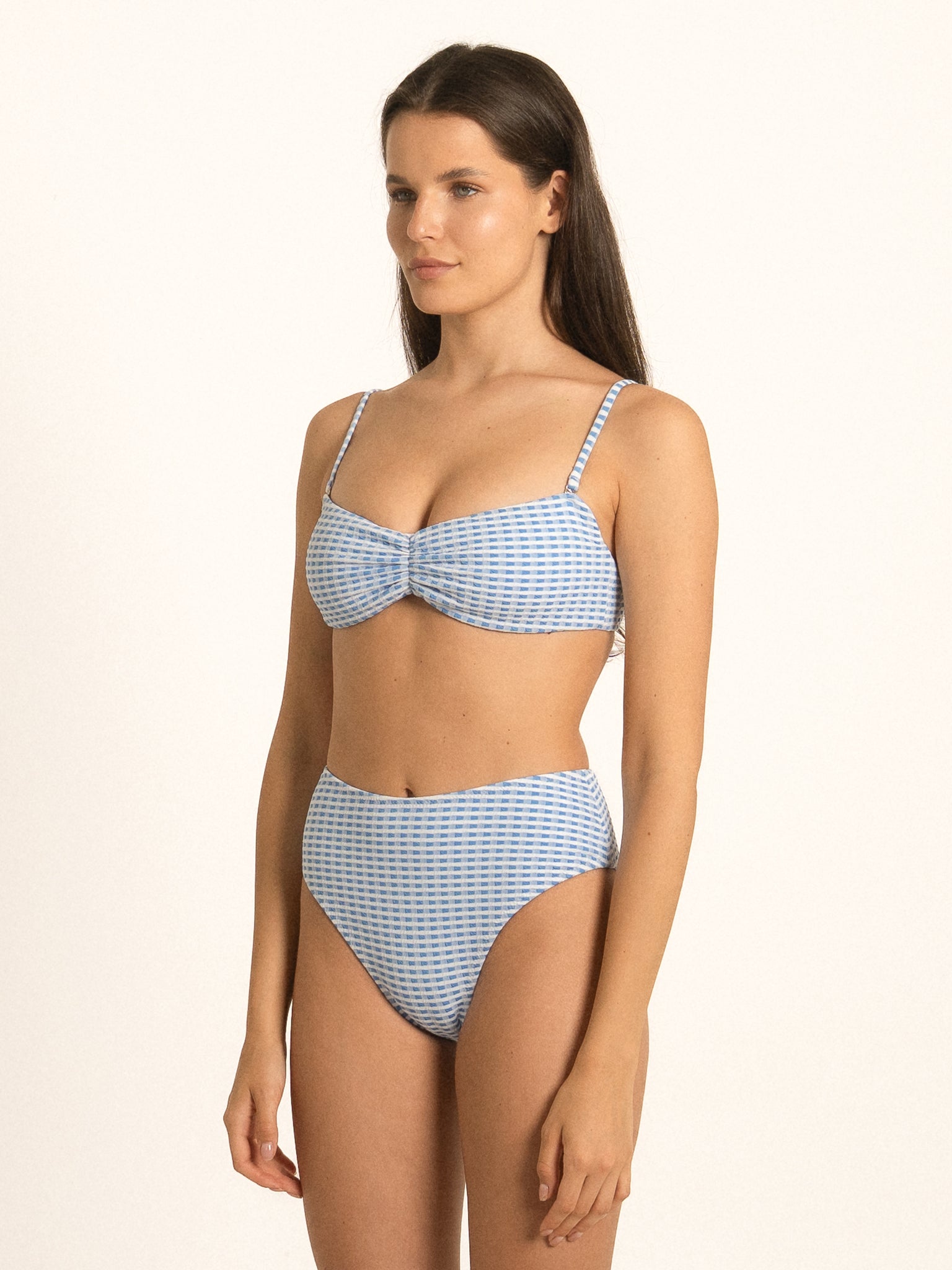 Model wearing Ocean Mystery blue gingham sweetheart bikini top with structured shape and elegant neckline.