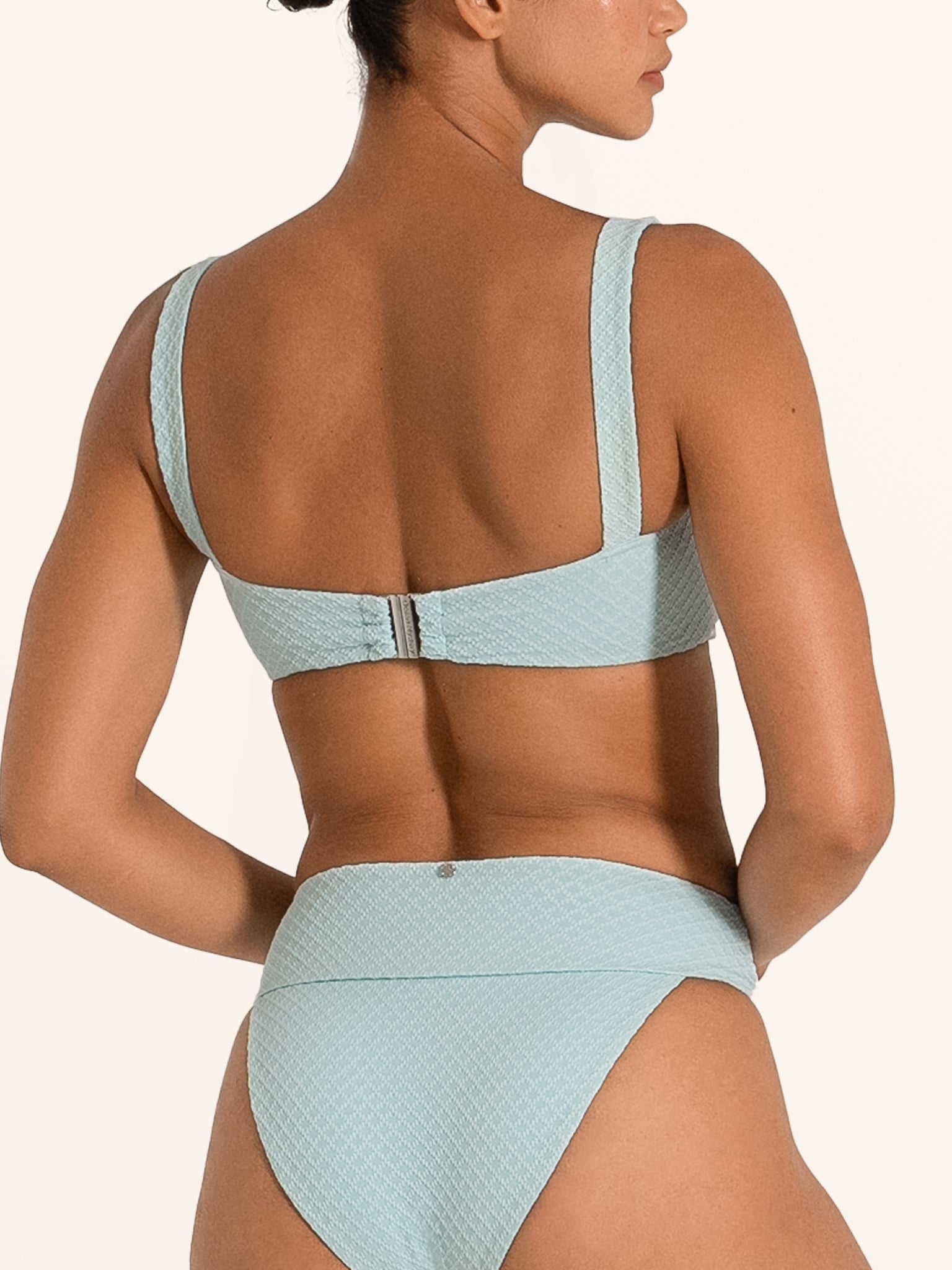 Model wearing Ocean Mystery textured bikini top in light blue with wide straps.