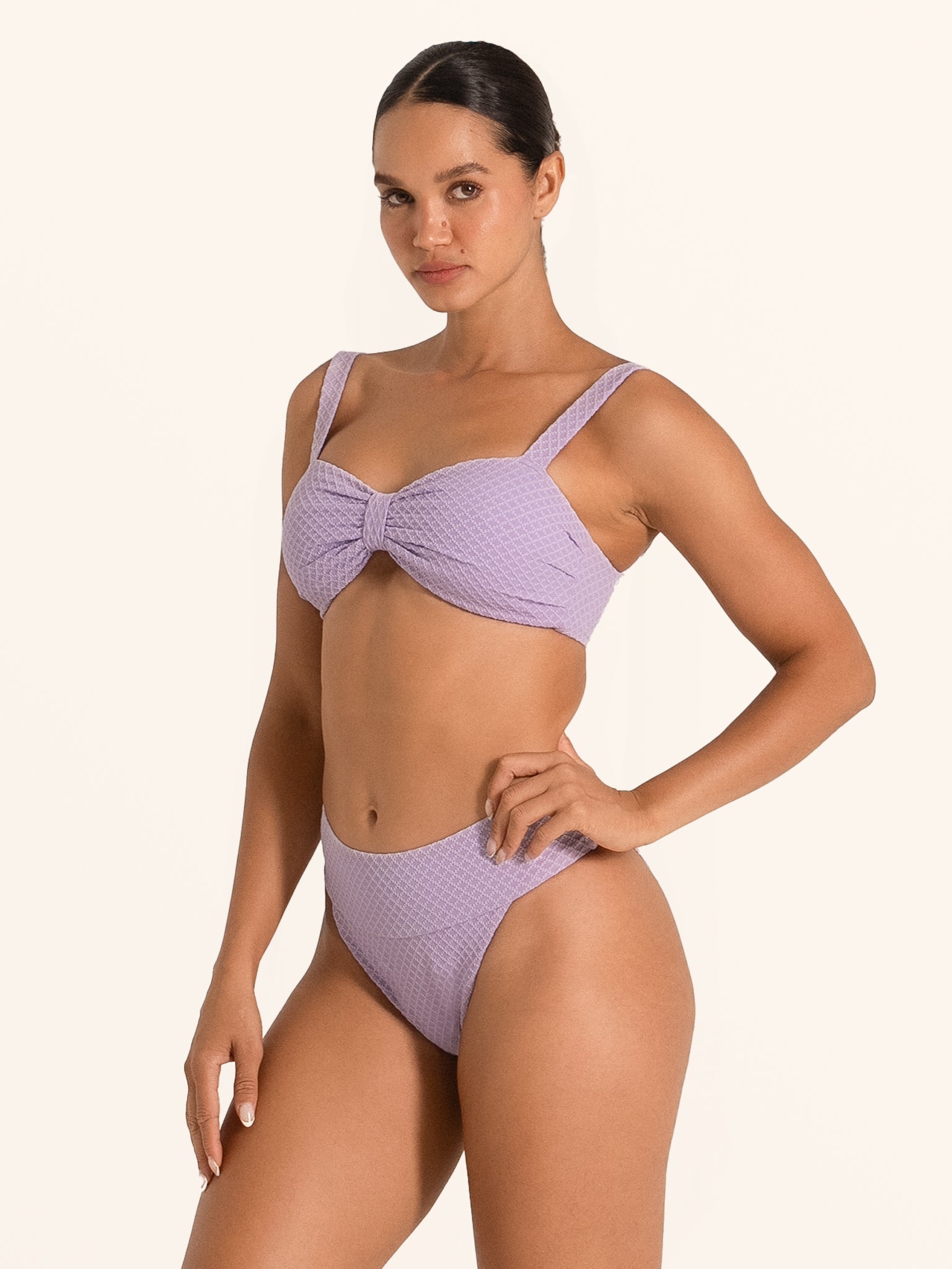 Model wearing Ocean Mystery lilac bikini bottom with high leg cut and textured fabric.