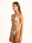 Model wearing Ocean Mystery light blue triangle bikini top with halter neck tie and minimal coverage.