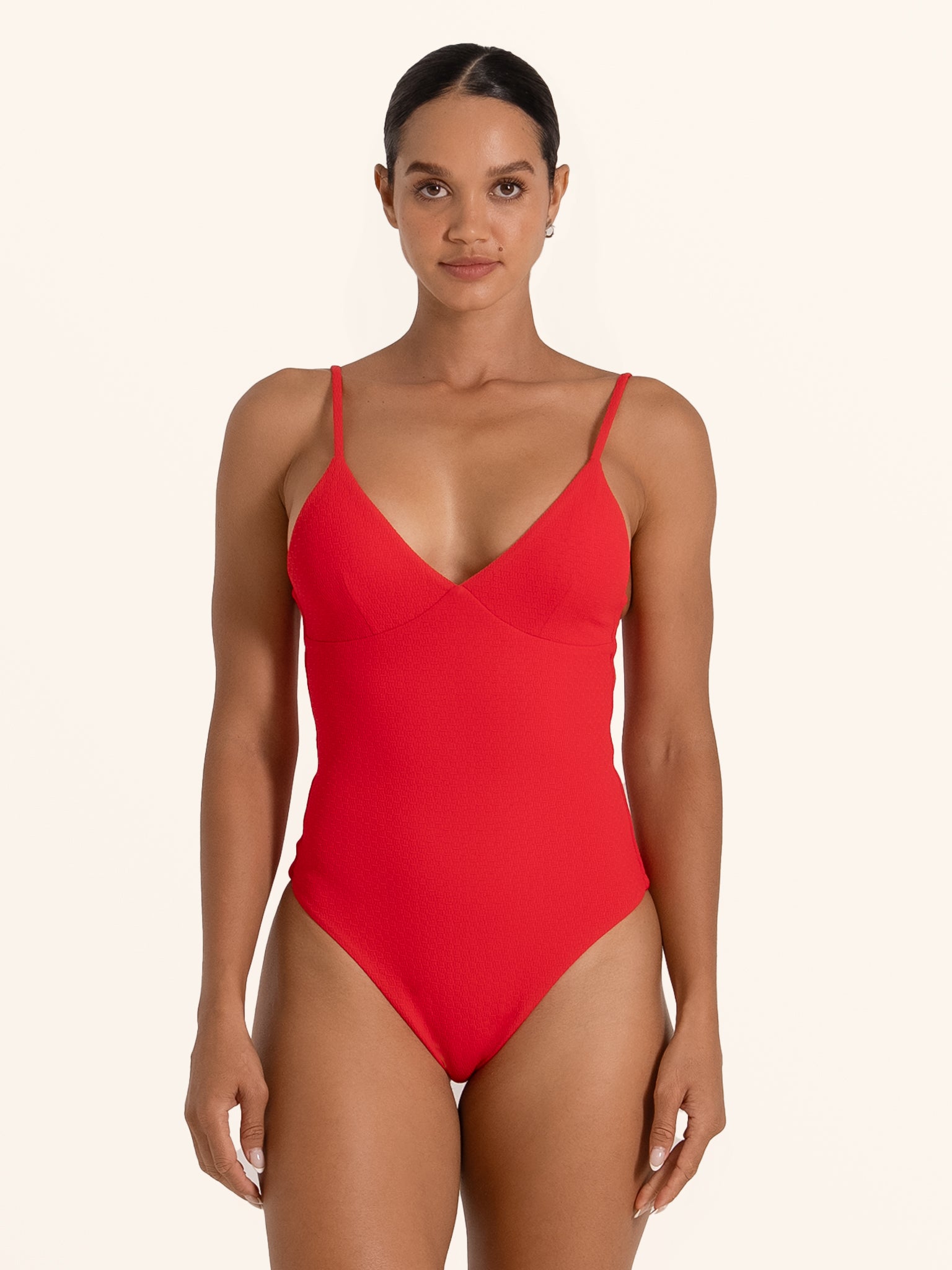 Front view of woman wearing red one piece swimsuit with V neckline and thin straps.