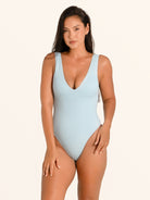 Front view of woman wearing baby blue textured one piece swimsuit with deep V neckline.