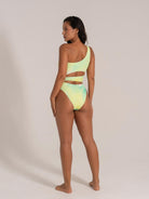 Woman wearing a one-shoulder monokini in green-yellow gradient with side cutouts – trendy asymmetric swimwear look