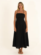 Front view of a woman wearing the Ocean Mystery Onyx pure linen midi dress, showcasing the minimalist straight neckline and flowy silhouette.