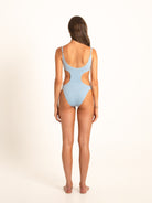 Rear shot of model in light blue cut-out swimsuit showing scooped open back and cheeky fit
