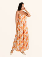 Side angle of orange floral maxi dress with tiered skirt and lightweight fabric
