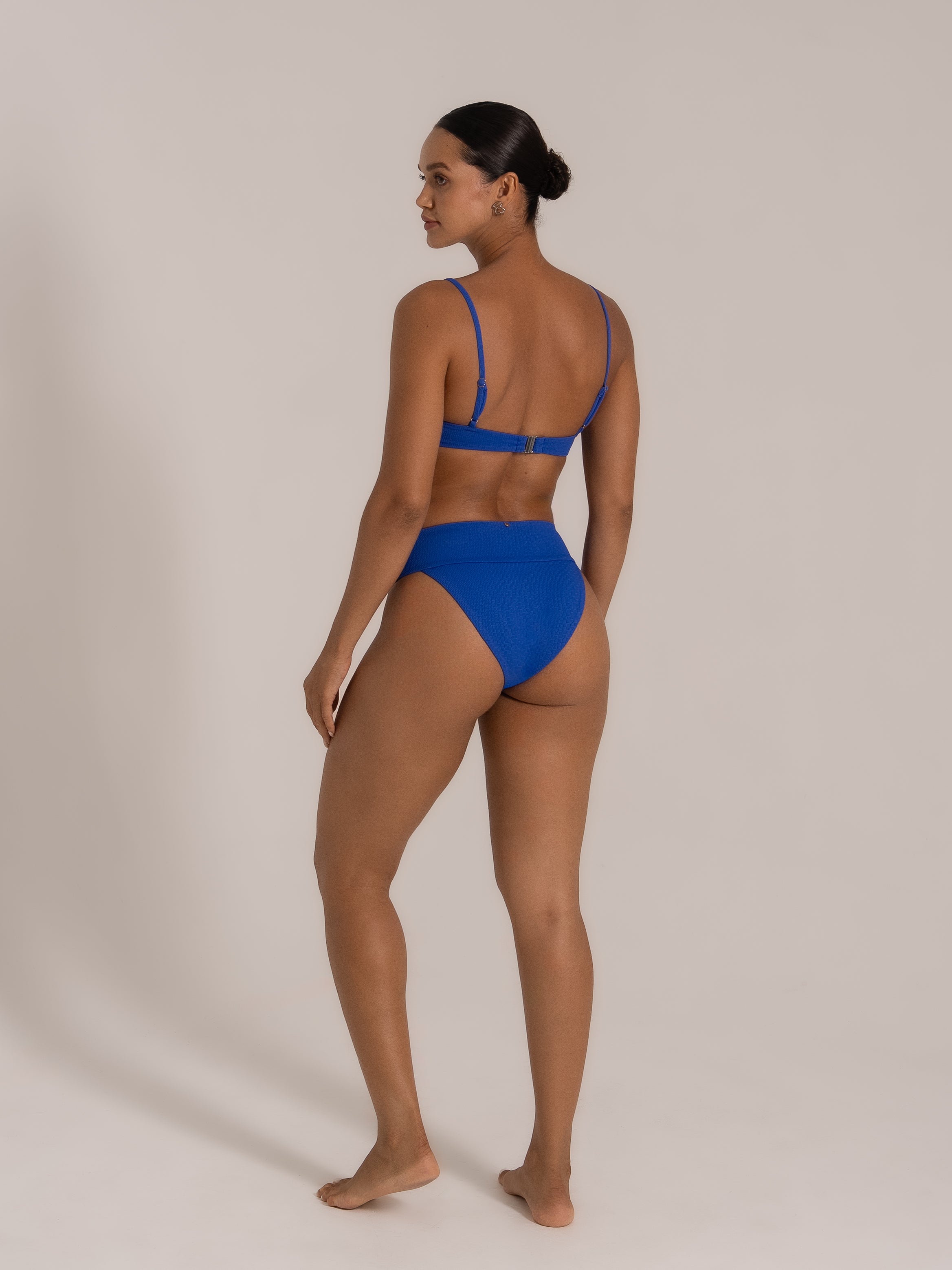Model wearing royal blue ribbed bikini set with adjustable straps and high waist bottom, back view.