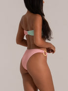 Side view of pastel pink high-leg bikini bottom with ring detail and textured fabric.