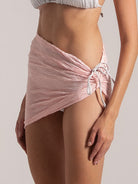 Pastel pink mini sarong bikini cover-up with ruched detailing, perfect for beach layering.