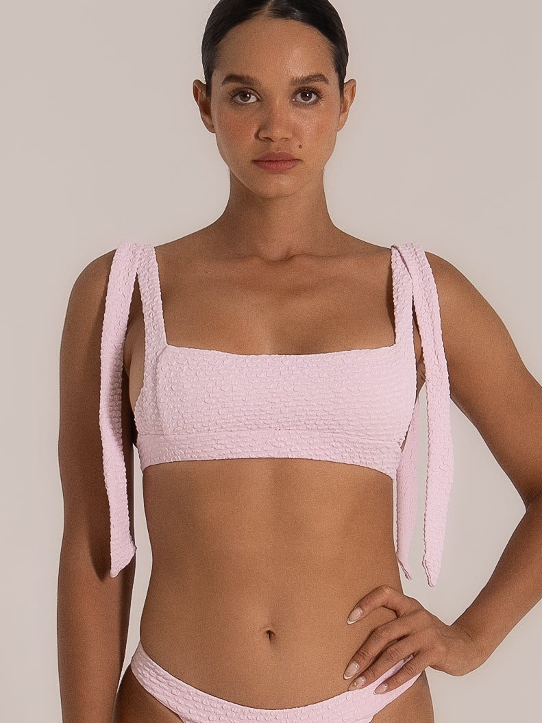 Front close-up of pink bikini top with thick textured fabric and square neckline