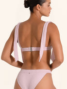 Pink bikini top with wide shoulder straps and chic summer look.