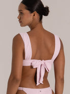 Back view of pink textured bikini top with wide shoulder straps and bow tie detail