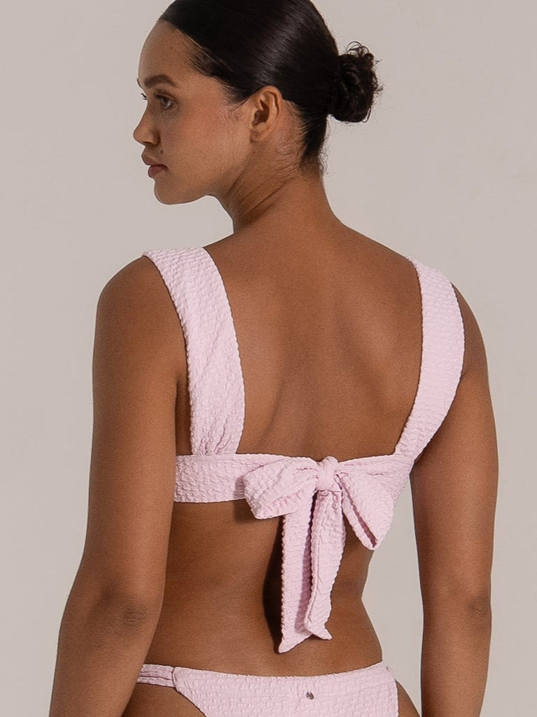 Back view of pink textured bikini top with wide shoulder straps and bow tie detail