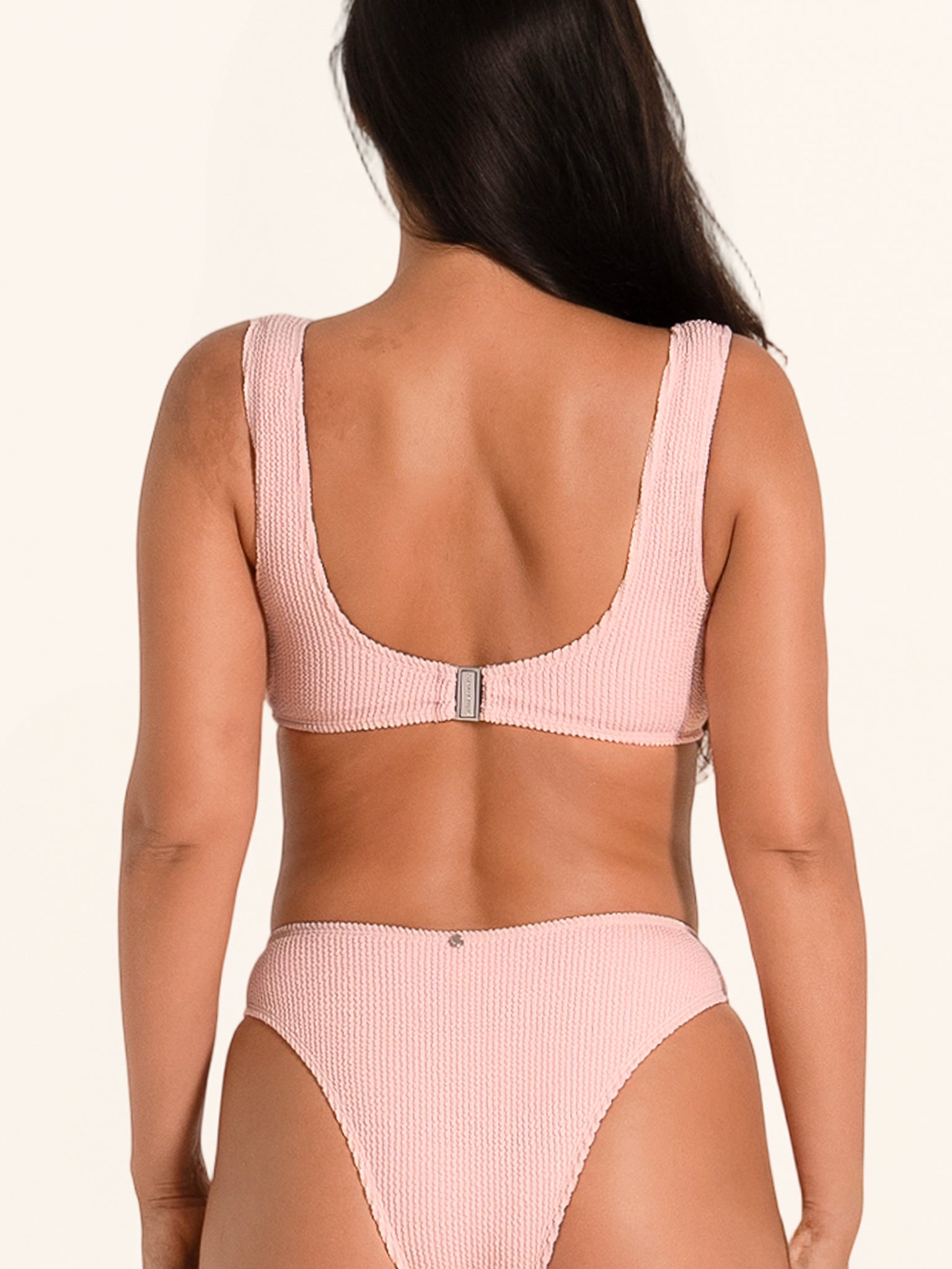 Pink swim top with decorative front ring and supportive straps.