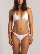 Model wearing full bikini set featuring light pink string tie bottoms and matching triangle top
