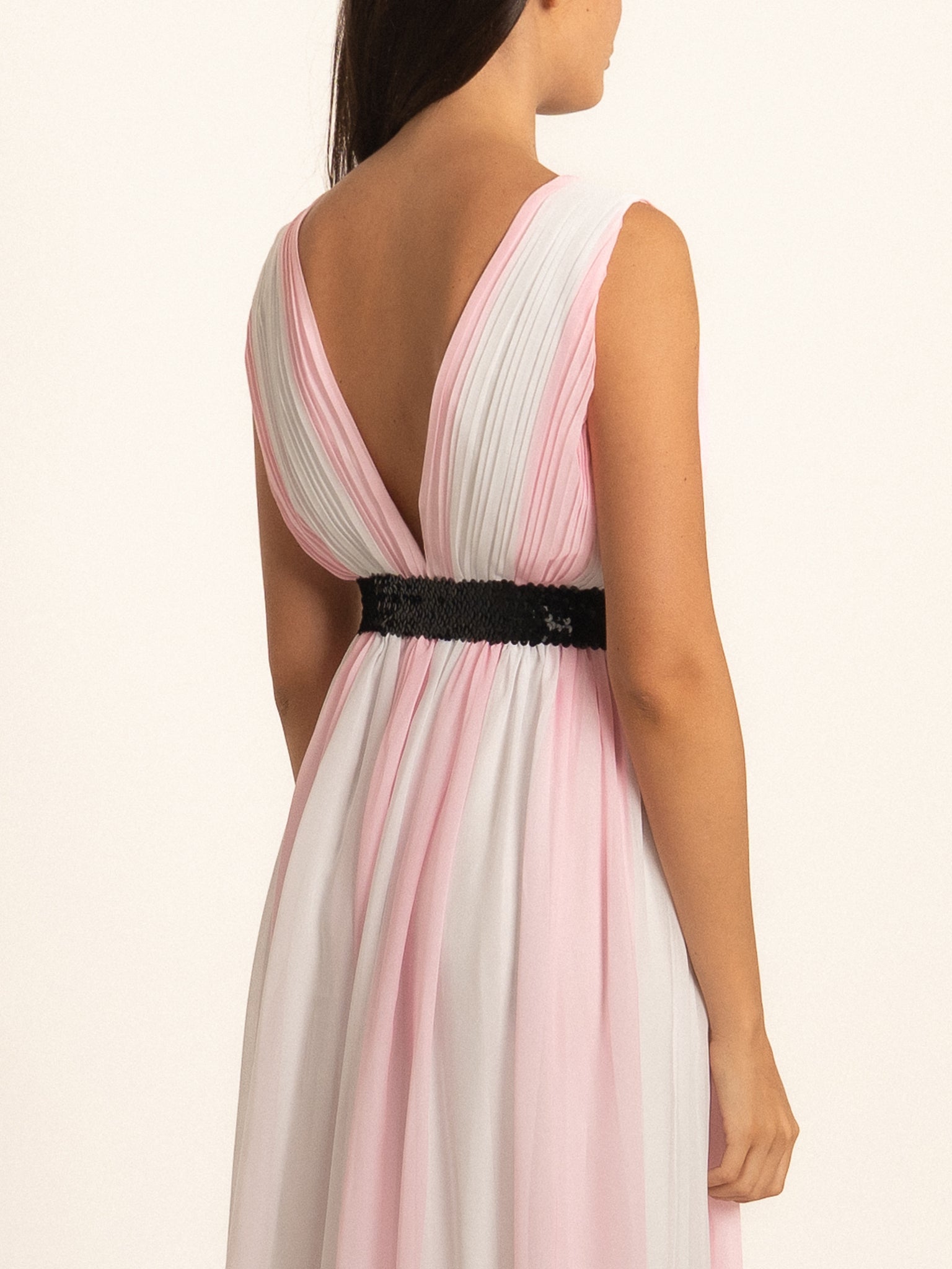 Back view of pink V neck maxi dress with pleated skirt and waist belt