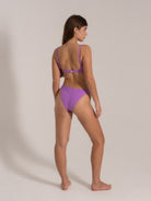 Model wearing purple bikini set with adjustable straps, side back view