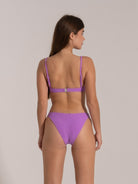 Model wearing purple textured bikini set viewed from the back with adjustable straps and clasp closure.