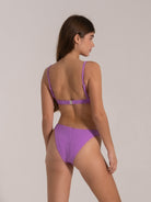 Woman in purple textured bikini with zebra pattern, showing back view and fixed shoulder straps