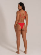 Back view of model wearing red bikini set with thin adjustable straps and cheeky bottoms.