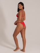 Side back view of red bikini with triangle top and minimal coverage bottom.