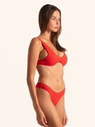 Three-quarter angle of red bikini top highlighting modern cut design.