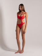 Angled front view of red cut-out swimsuit with spaghetti straps and curved ring cut design