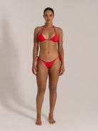 Model wearing red halter bikini set with triangle top and side-tie bikini bottoms, front view