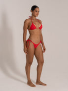 Model in red textured bikini set showing side angle with halter top and tie-side bottoms