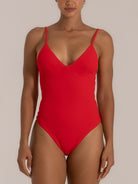 Front view of a woman wearing a bold red one-piece swimsuit with a deep V neckline and thin adjustable straps, offering a flattering and sleek silhouette.