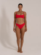 Model posing in a red bikini set with square neckline and minimalistic silhouette.