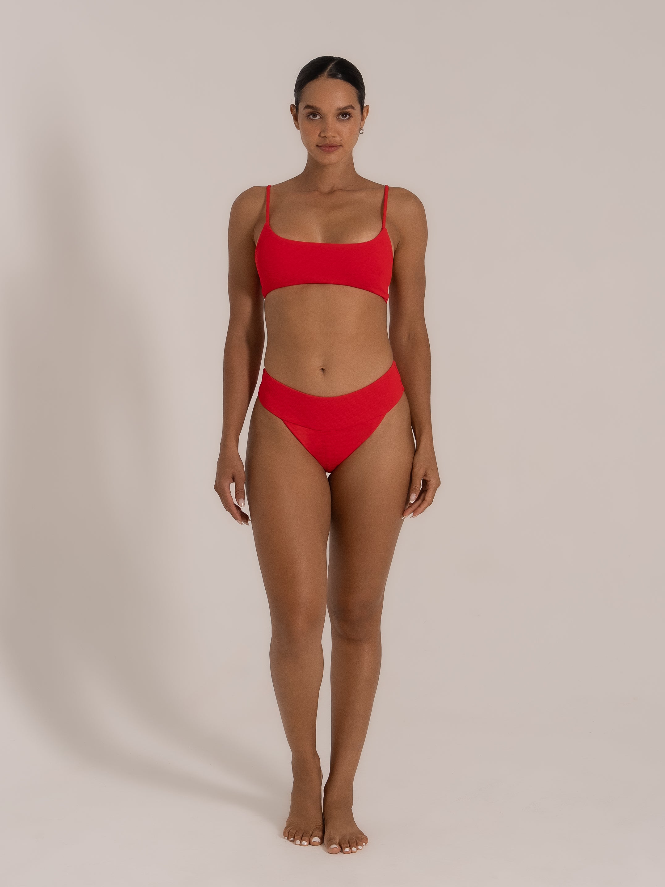 Model posing in a red bikini set with square neckline and minimalistic silhouette.