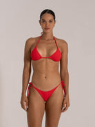 Woman modeling a red textured triangle bikini set from the front, featuring tie-side bottoms.