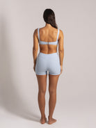 Full back view of a woman wearing a ribbed light blue bikini top and matching high-waisted shorts