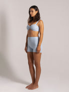 Side view of a woman in a light blue ribbed bikini top with matching high-waisted shorts
