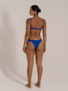 Model wearing a royal blue bikini set with scoop neck top and adjustable thin straps, back view.