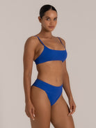 Side angle of royal blue fold-over bikini bottom paired with scoop neck bikini top