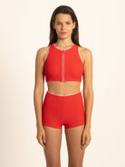 Full front view of the Ruby red zip front tank crop top, offering an elegant athletic look with contrast white piping on the ribbed fabric.