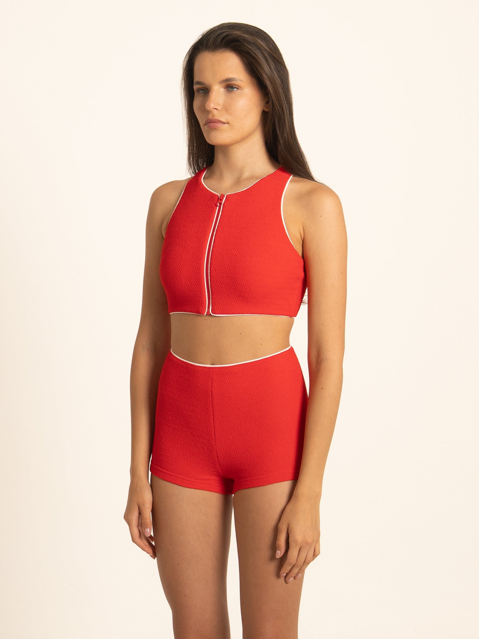 Side profile view of the Ruby red front zip tank swim top, highlighting the sports support and sleek athletic fit with thin white piping details.