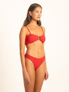 Front profile view of the Ruby red ribbed bikini top featuring a center resin ring and removable straps, paired with matching high-cut bottoms.