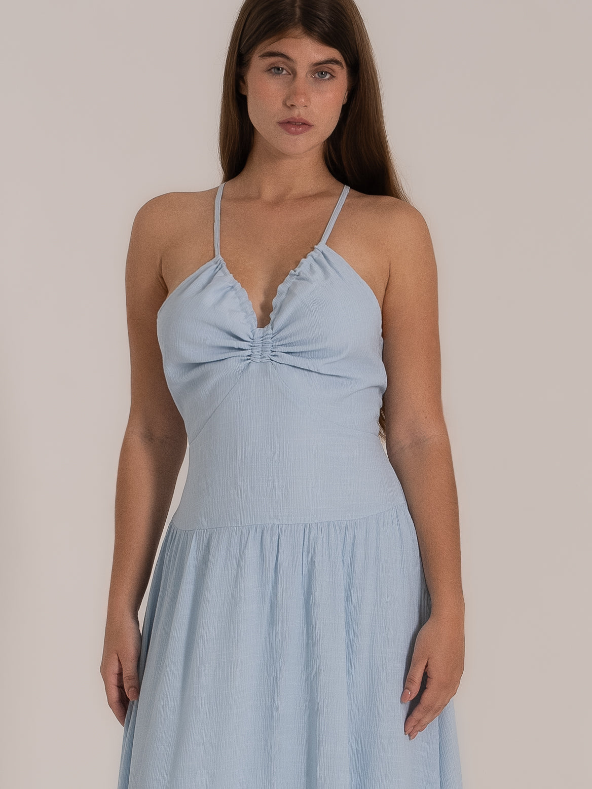 Front view of a ruched sky blue sundress with spaghetti straps and a flowy silhouette.