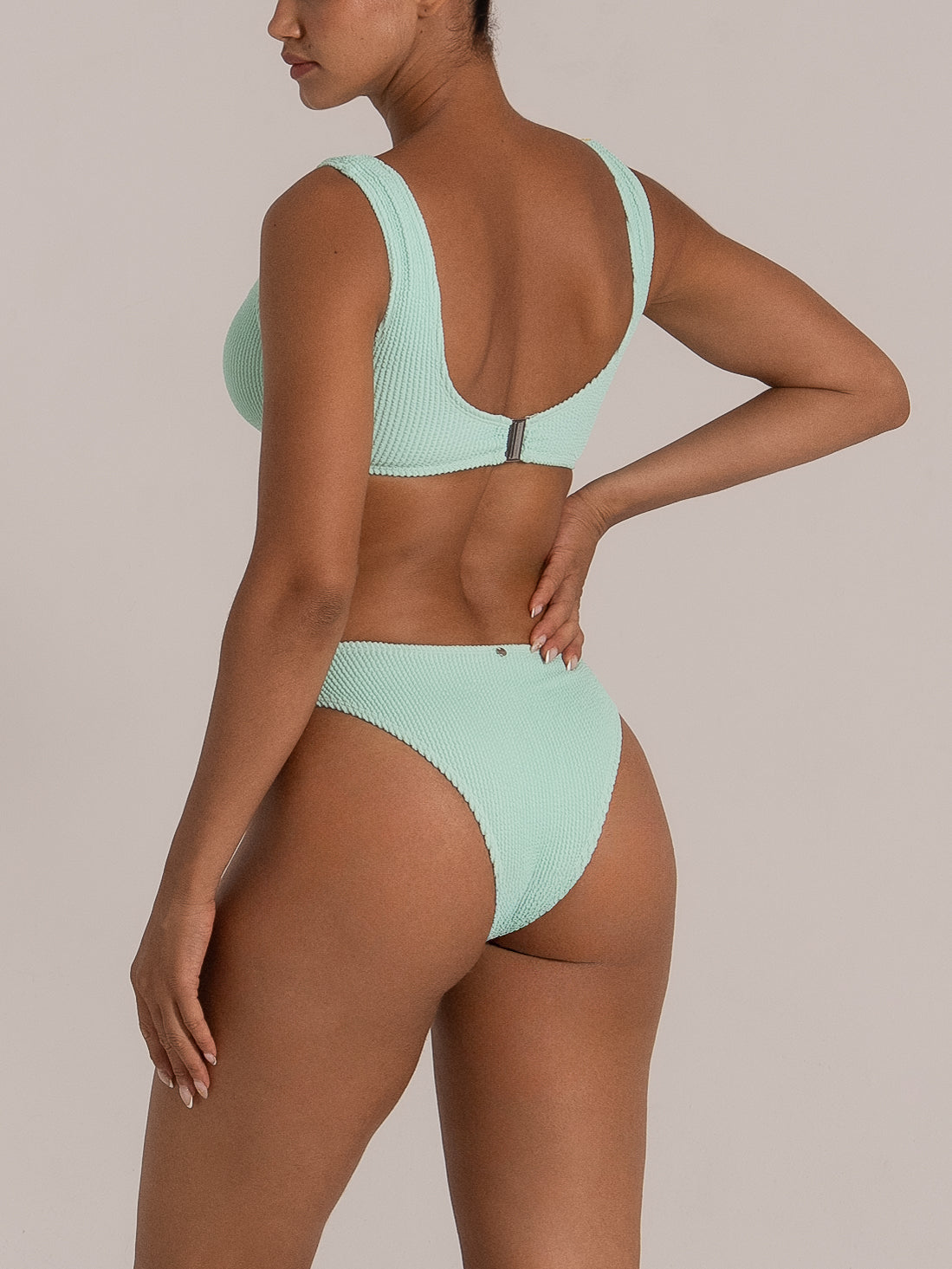 Side angle showcasing the high-rise cut and ribbed texture of mint green bikini bottom