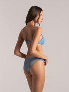 Side view of model in blue bikini set with adjustable straps and mid-rise bottom